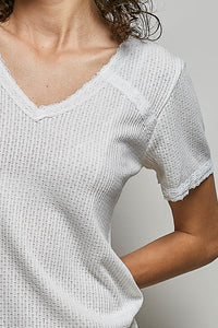 Close-up of a person wearing a textured white top against a neutral background