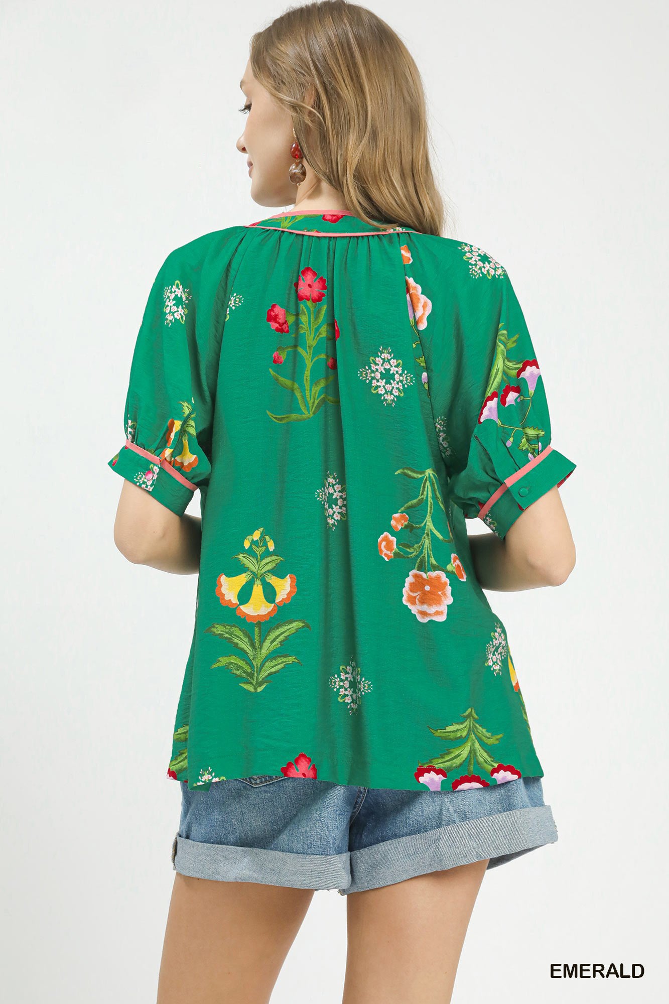 Green embroidered top worn by a person on a white background