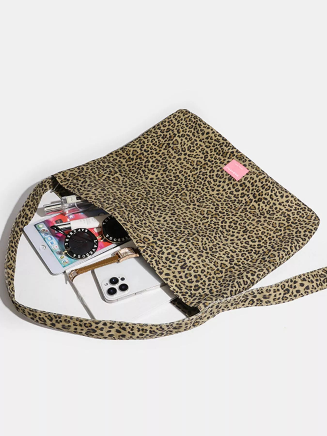 Leopard print crossbody bag with phone and cards on a white background