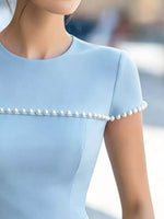 Light blue dress with pearl embellishments on a blurred background