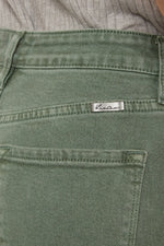 Close-up of green pants with a brand label on a blurred background