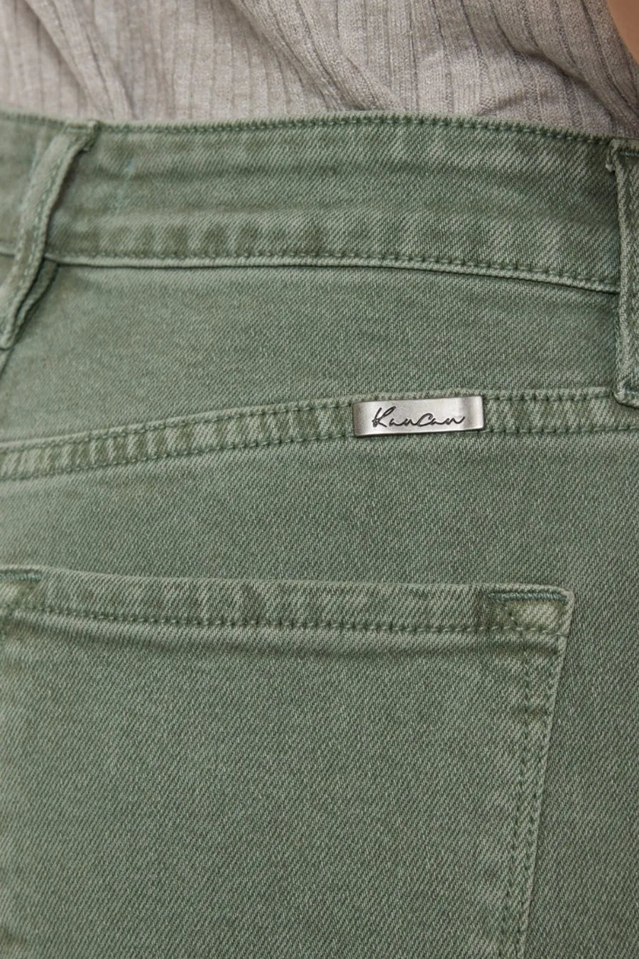 Close-up of green pants with a brand label on a blurred background