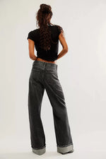 Person wearing black t-shirt and gray jeans from behind on a white background