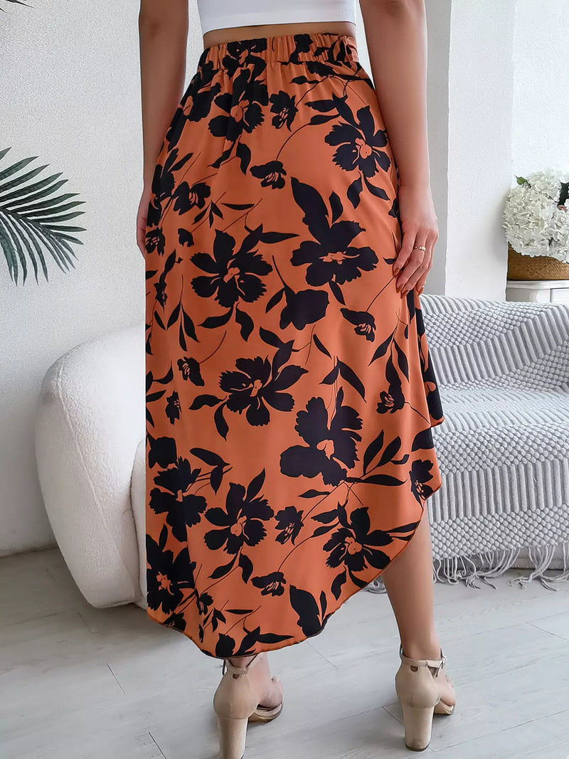 Person wearing an orange skirt with black floral pattern in a room.