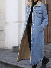 Person wearing a long denim coat with beige lining outdoors.