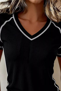 Black ribbed sweater with white trim on a plain background