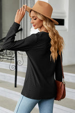Woman wearing a black long-sleeve top, light blue jeans, and a brown hat, holding a brown handbag.
