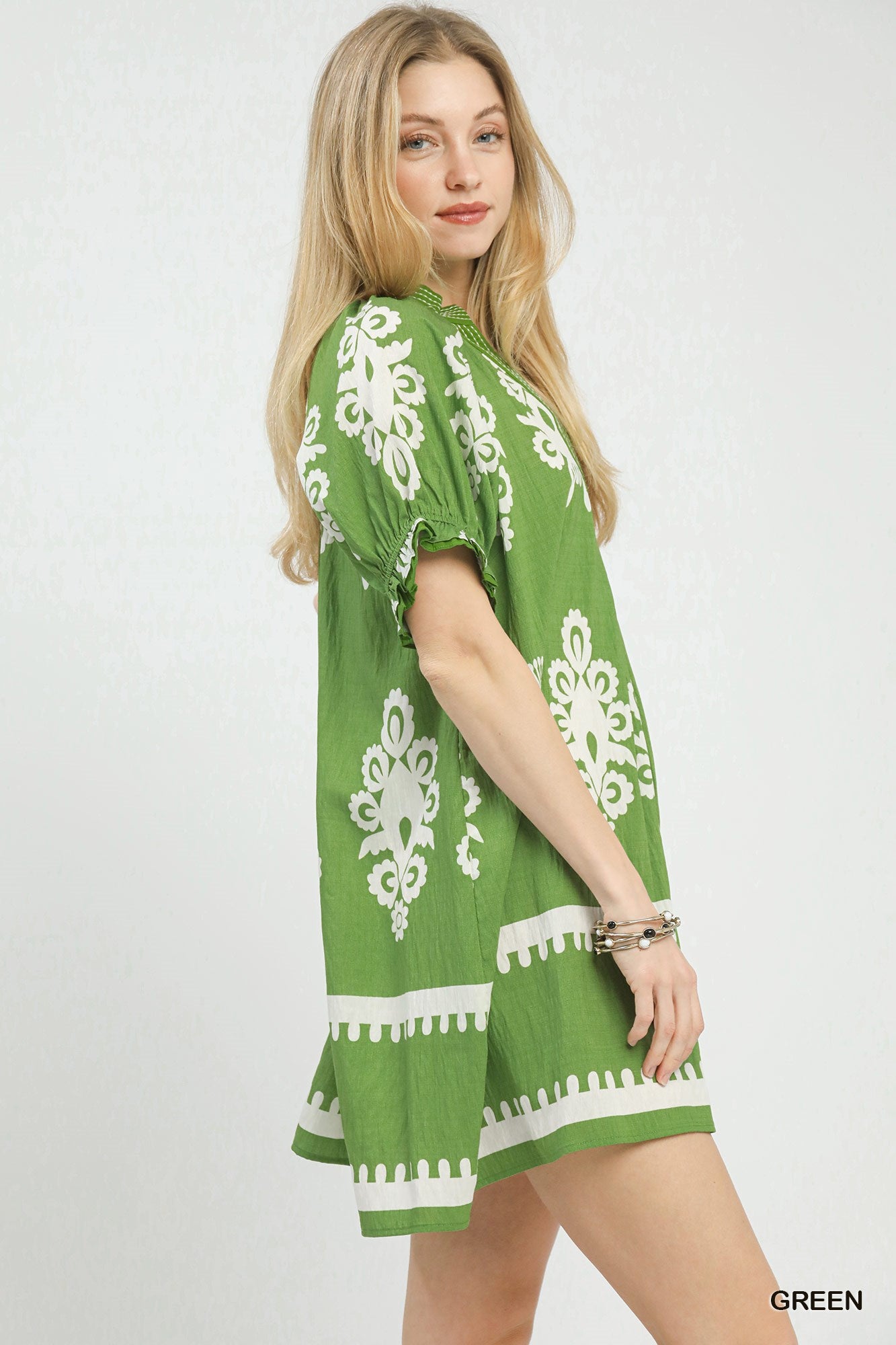 Woman wearing a green dress with white patterns on a white background