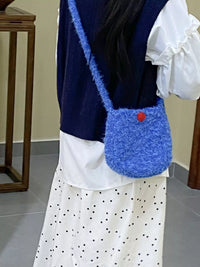 Person wearing a blue knitted bag with a red button on a neutral background