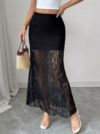 Person wearing a black lace skirt with a white top and holding a straw bag.