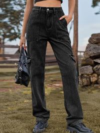 Person wearing black cargo pants holding a black bag outdoors.
