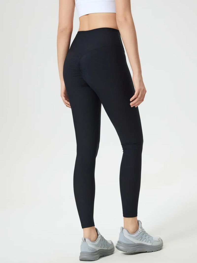 Person wearing black leggings and light gray sneakers on a white background