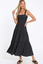 Woman wearing a black tiered dress on a white background