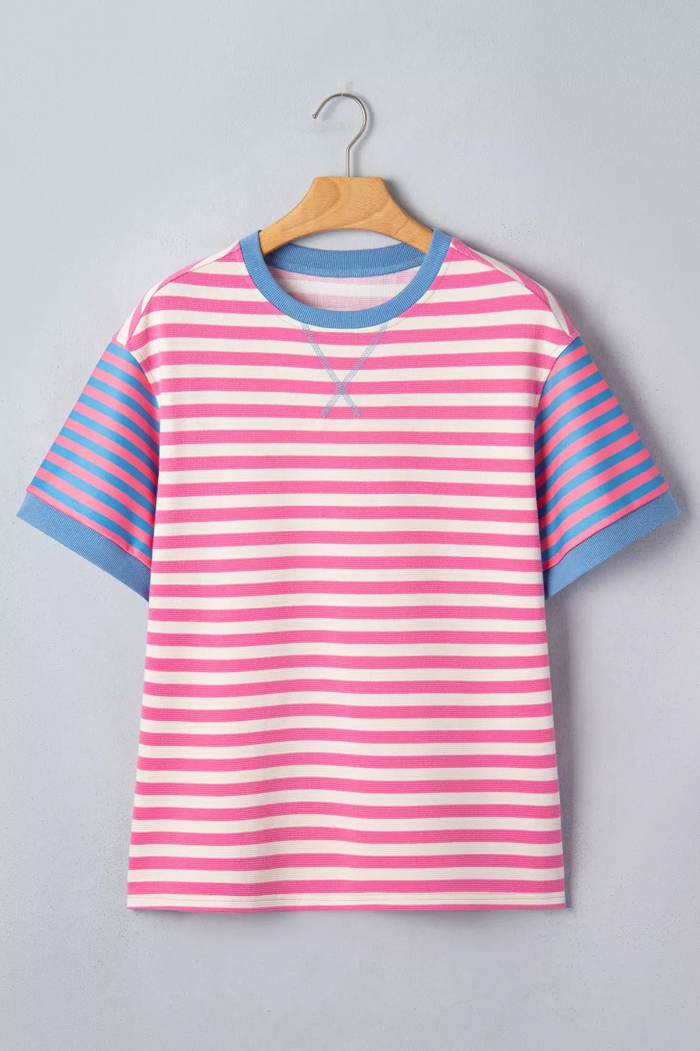 Pink and blue striped shirt on a hanger against a gray background