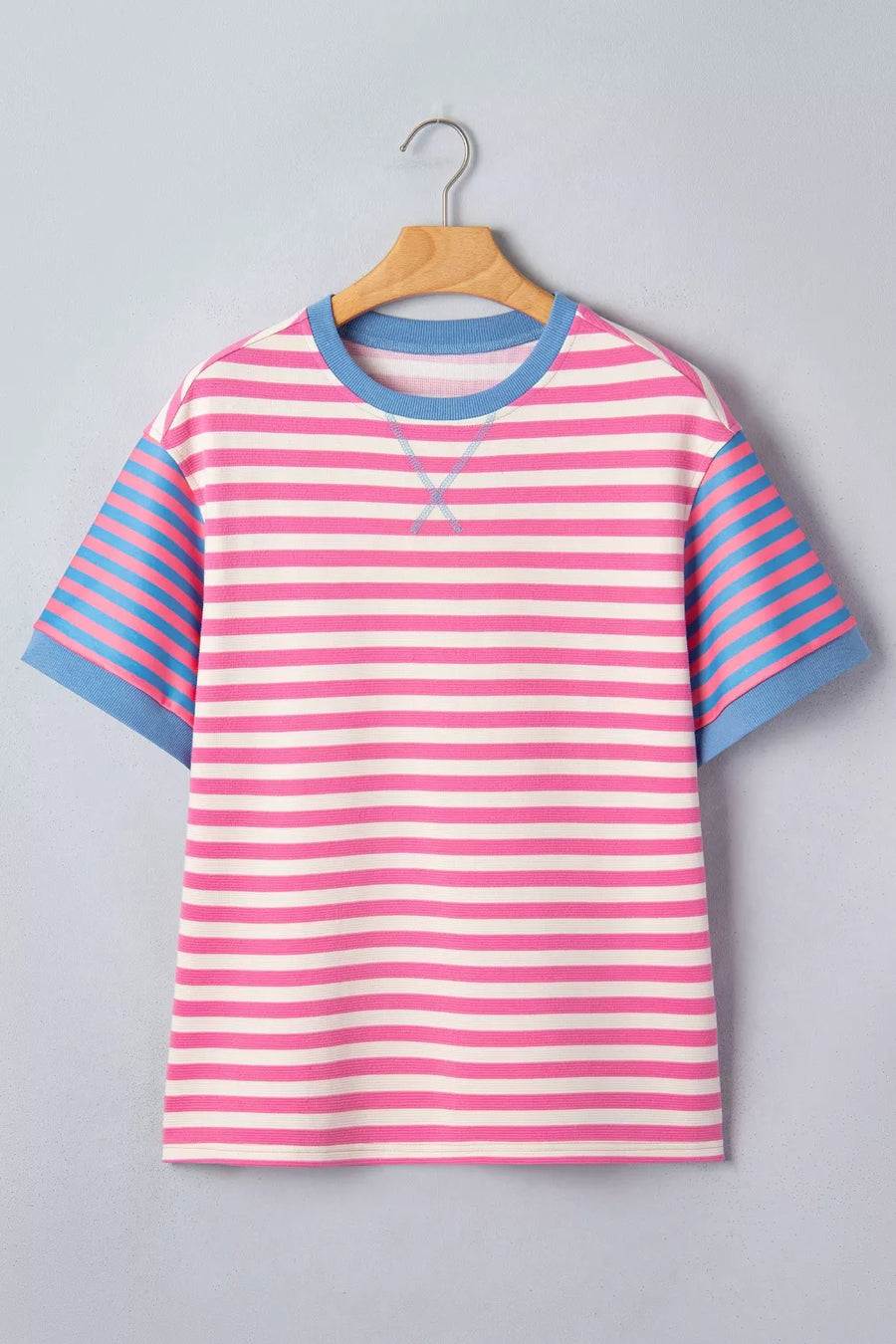 Pink and blue striped shirt on a hanger against a gray background