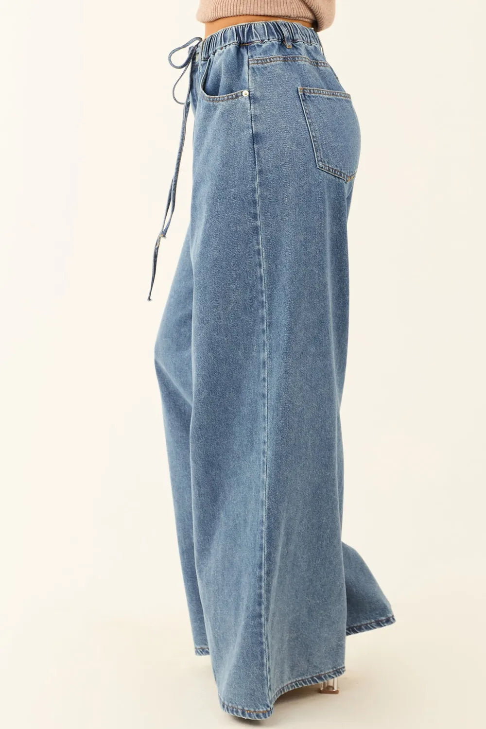 Blue denim wide-leg pants with a tie-waist on a white background