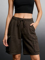 Person wearing brown cargo shorts and a black top on a gray background