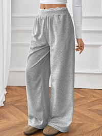 Person wearing gray sweatpants on a wooden floor.