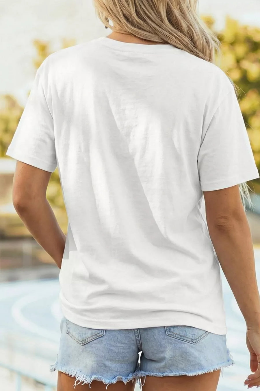 Person wearing a plain white t-shirt and denim shorts with a blurred natural background