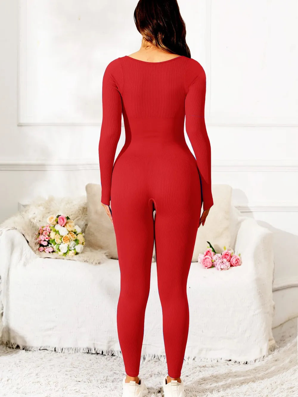 Person wearing a red jumpsuit in a room with white walls and a couch.