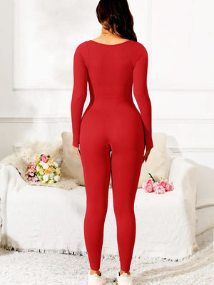 Person wearing a red jumpsuit in a room with white walls and a couch.