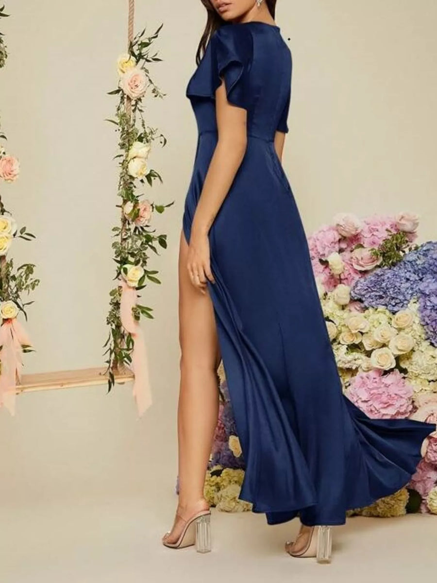Woman in a blue evening gown standing in front of floral decorations