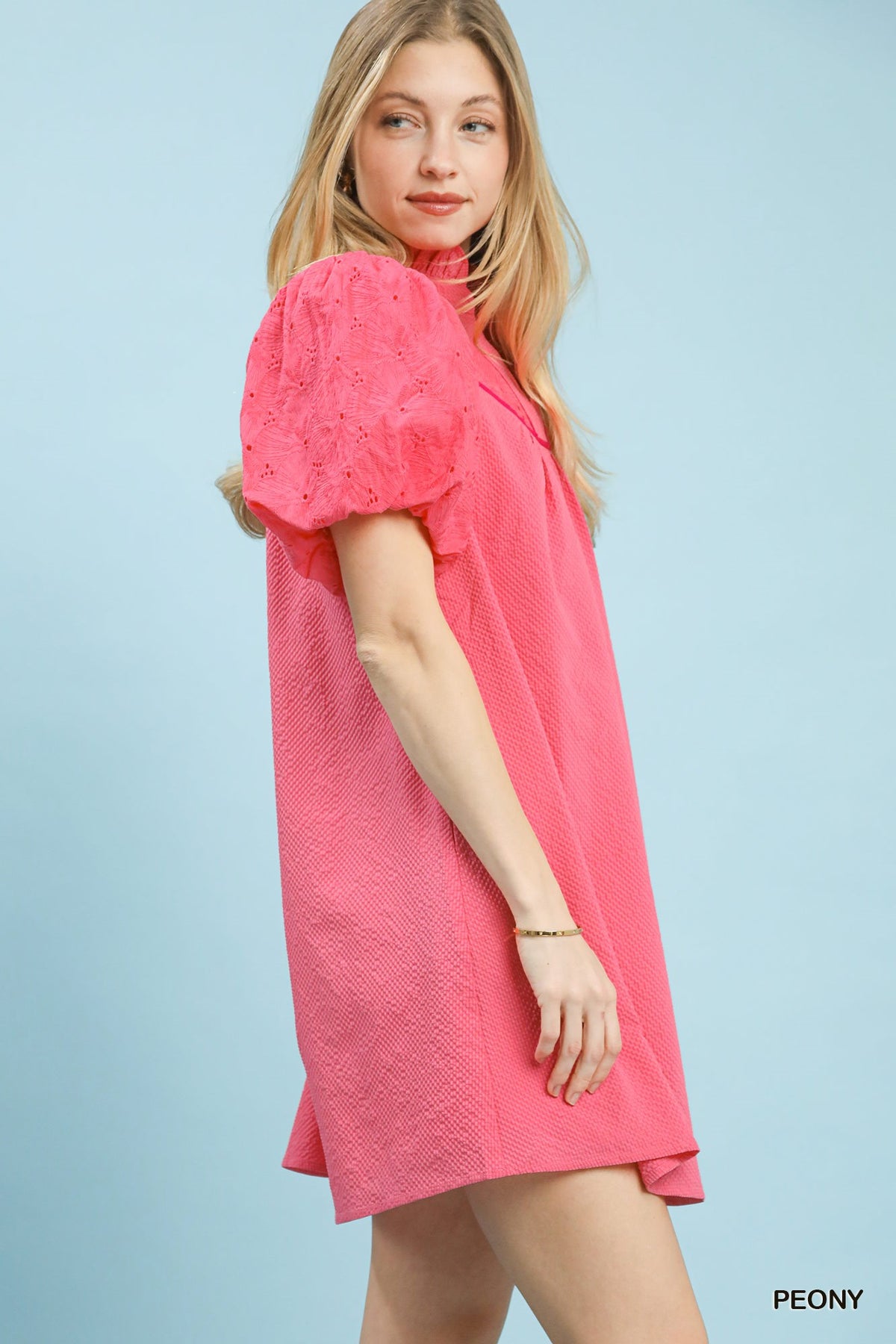 Woman wearing a pink dress against a light blue background