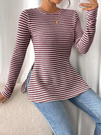 Person wearing a red and white striped sweater and blue jeans on a neutral background
