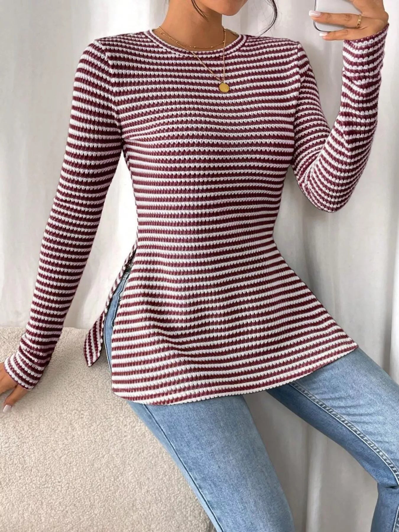 Person wearing a red and white striped sweater and blue jeans on a neutral background