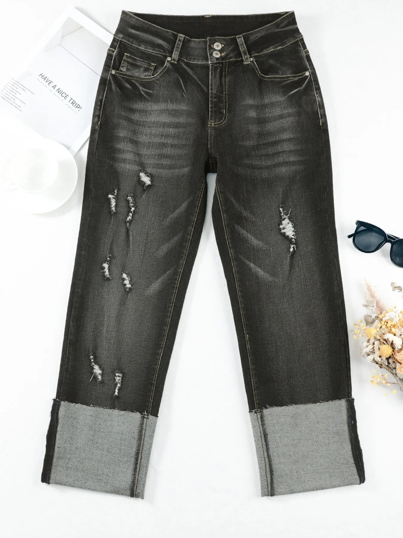 Black distressed jeans with gray patches on a white surface