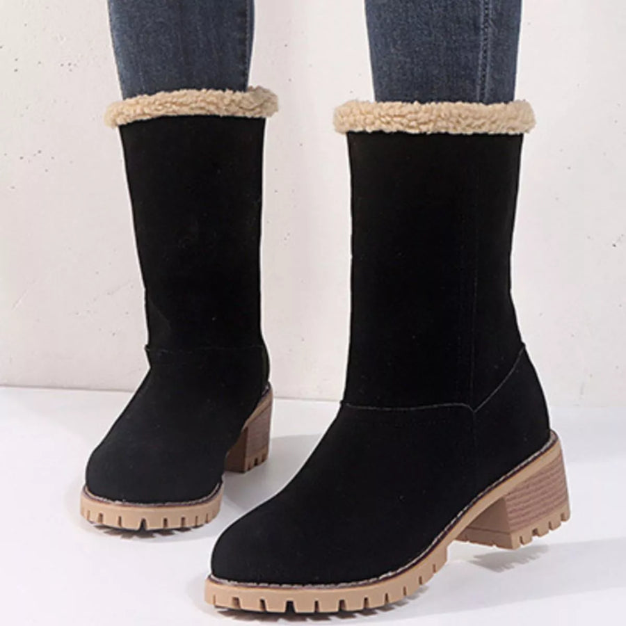 Black boots with beige fur lining and soles on a white background
