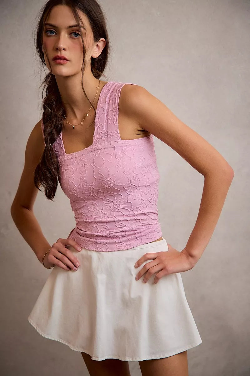 Woman wearing a pink top and white skirt against a neutral background