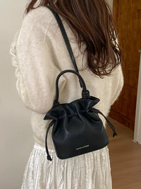 Person wearing a black drawstring bag over one shoulder indoors.