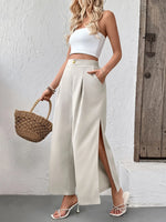 Woman wearing a white top and beige wide-leg pants with a straw bag against a neutral background
