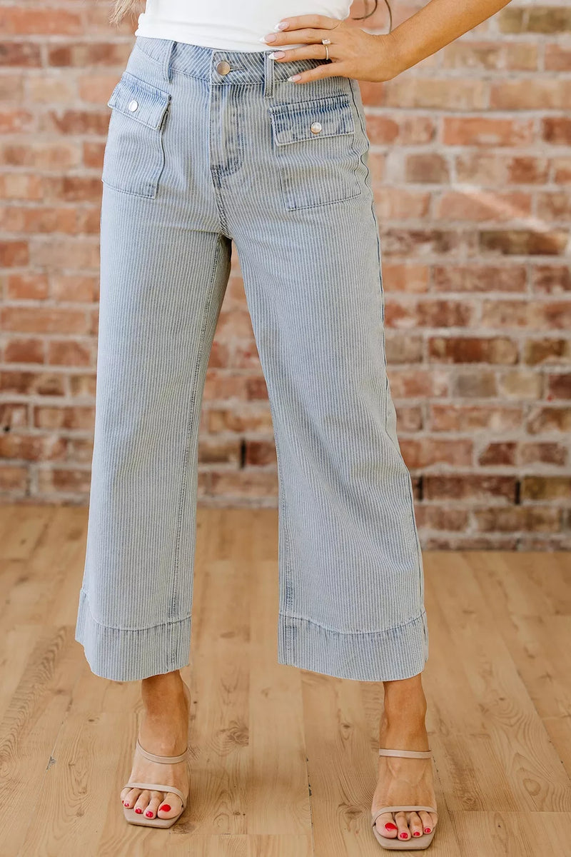 Light blue jeans worn by a person against a brick wall.