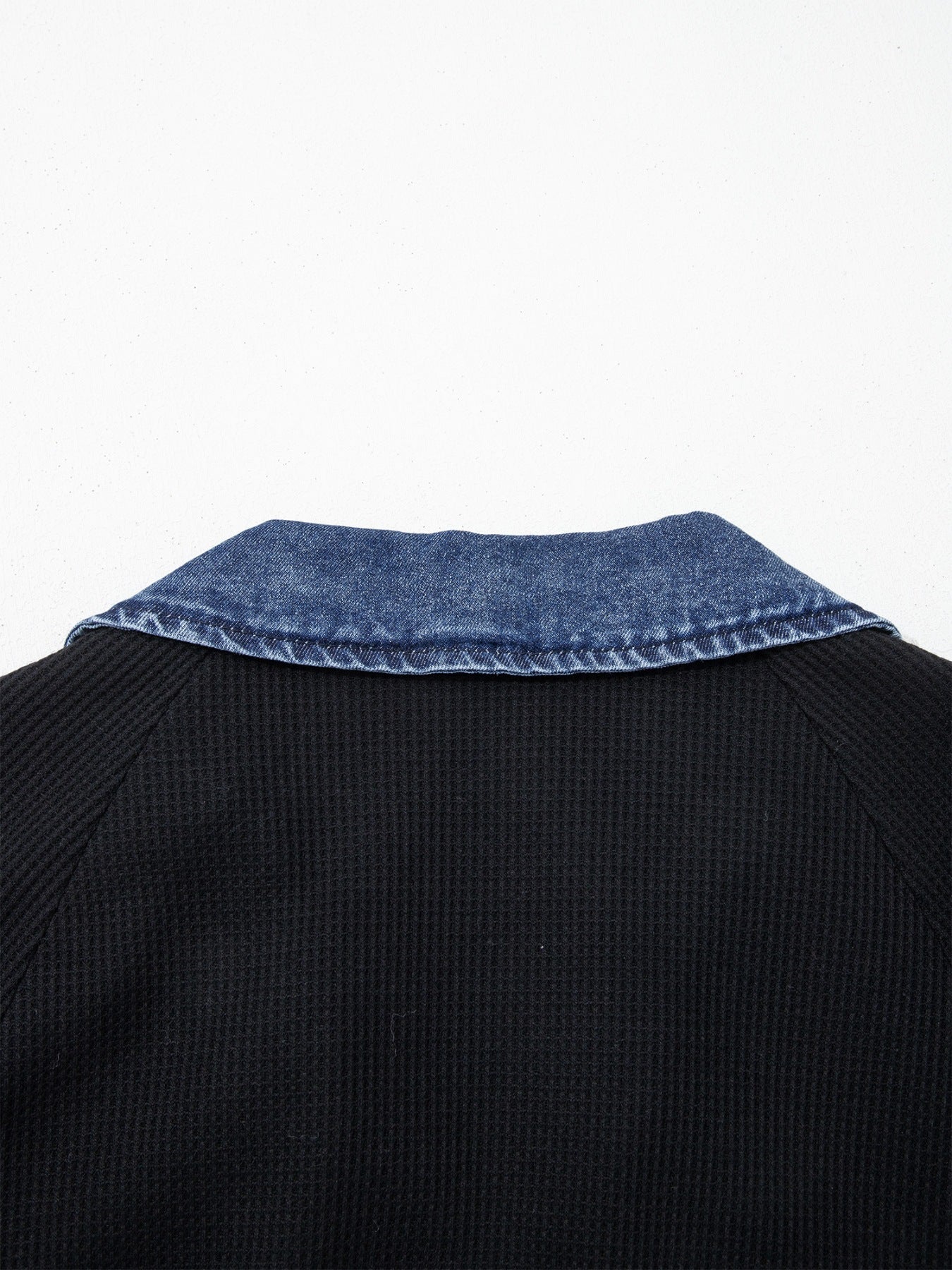 Black sweater with blue denim collar on a white background