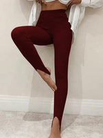 Person wearing maroon leggings with a white shirt in a minimalistic setting
