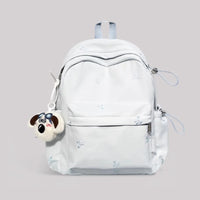White backpack with a dog-shaped keychain on a light gray background