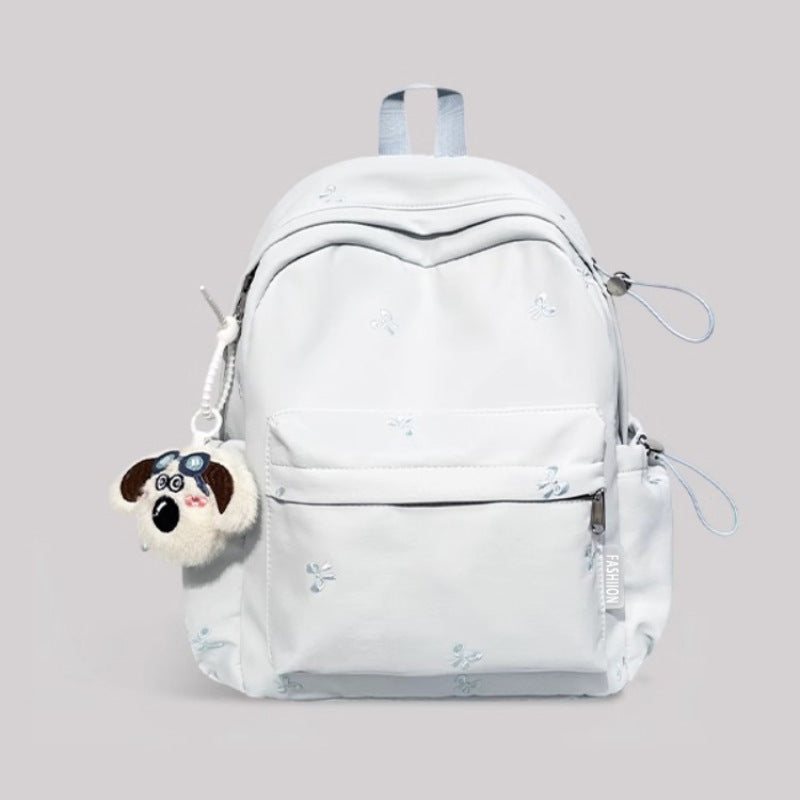 White backpack with a dog-shaped keychain on a light gray background