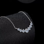 Silver necklace with clear stones on a black stand