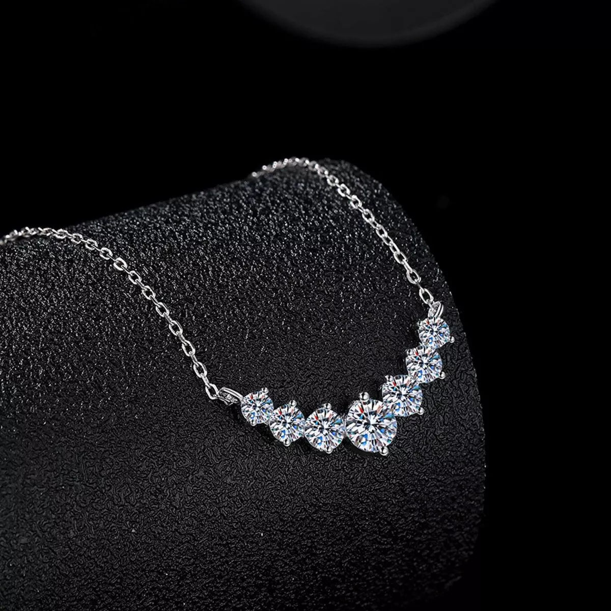 Silver necklace with clear stones on a black stand