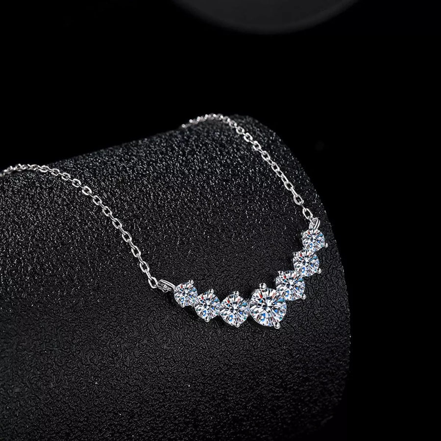 Silver necklace with clear stones on a black stand