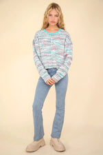 Woman wearing a colorful sweater and blue jeans on a beige background