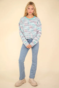 Woman wearing a colorful sweater and blue jeans on a beige background