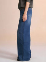 Person wearing blue jeans on a beige background