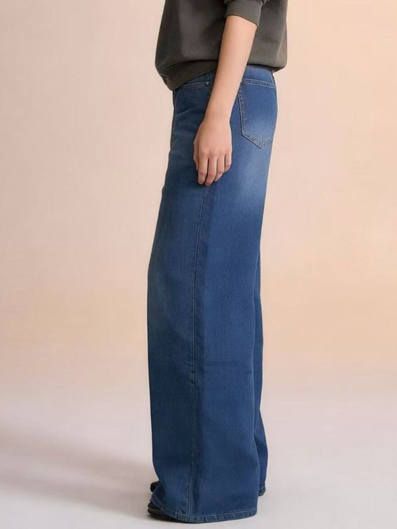Person wearing blue jeans on a beige background