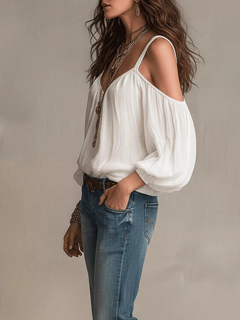 Woman wearing a white blouse with balloon sleeves and blue jeans against a neutral background