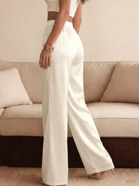 Person wearing white pants standing in a living room with a beige sofa.