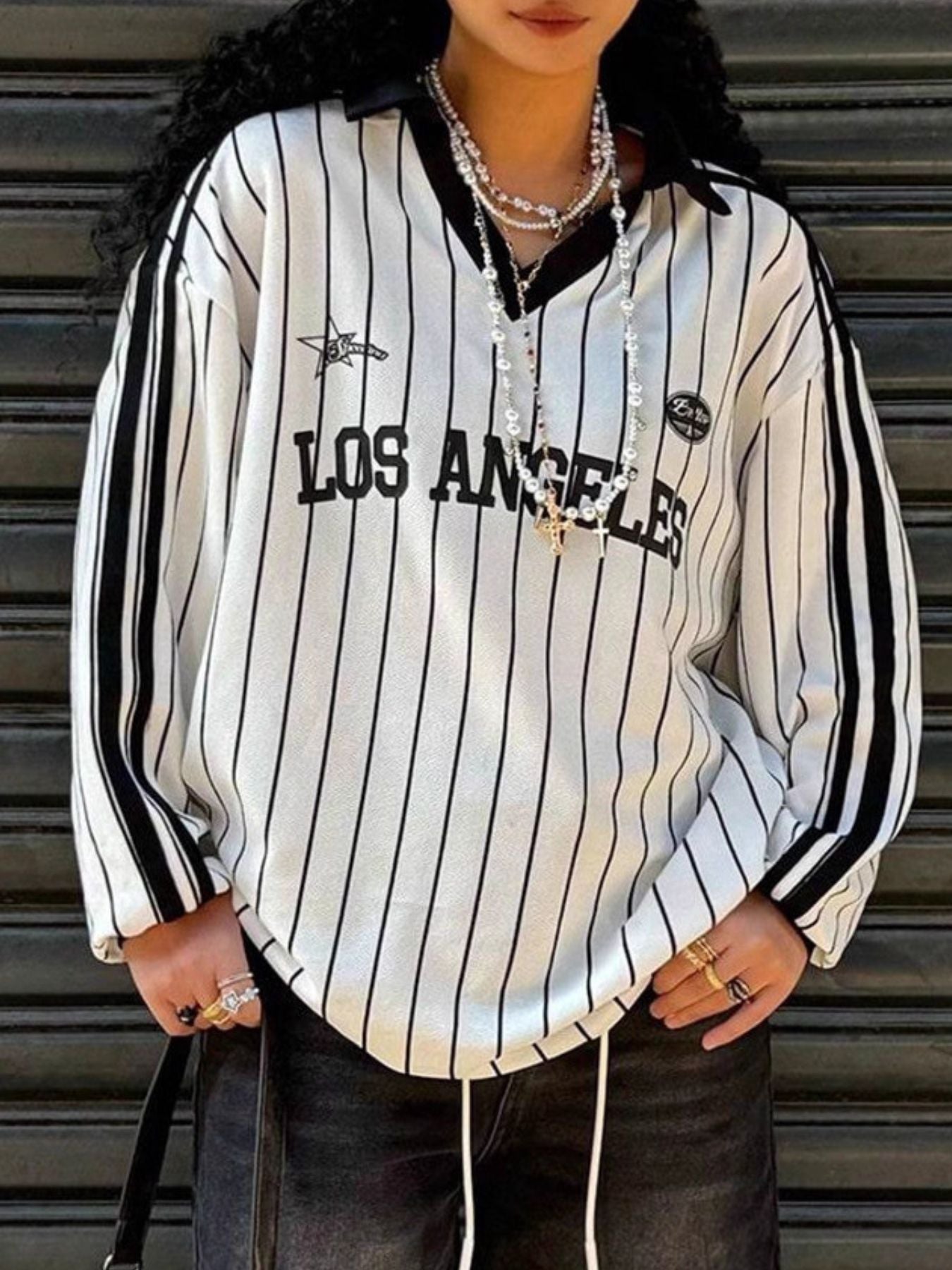 Person wearing a white and black striped shirt with 'Los Angeles' text against a metallic background