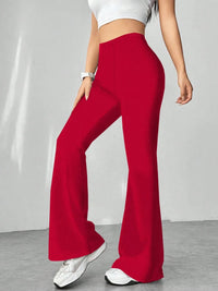 Red flared pants worn by a person on a gray background